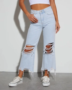 Dettaglio dei jeans azzurri con strappi sulle ginocchia e orli sfrangiati vintage