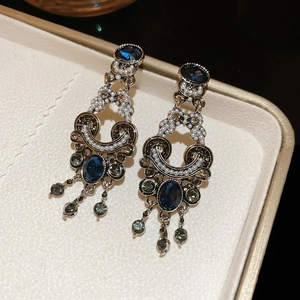 Macro shot of vintage baroque earrings with navy blue gems and delicate pearl tassels