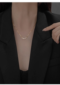 Detail of elegant gold-plated silver necklace with V-shaped zircon pendant on a model