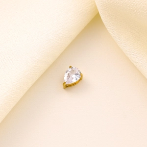 Detail of pear-shaped clear zircon charm with gold plating on soft silk background