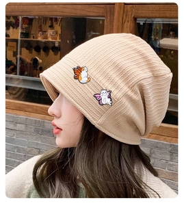 Détail de badges de chat mignons avec des ailes sur un bonnet en tricot beige