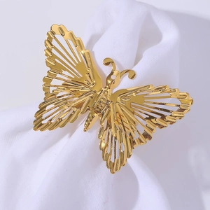 Golden metal butterfly napkin ring with intricate cutout wings on white fabric
