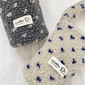Close-up of soft plush lamb fleece drink carriers featuring embroidered brand labels