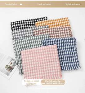 Detailed close-up of houndstooth cashmere scarfs in various colors with fringe tassels