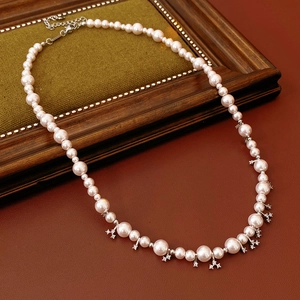 Detail of beaded pearl necklace with zircon pendant on a vintage green velvet surface