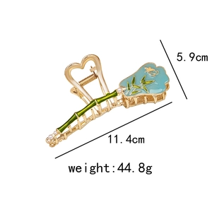 Detail of bamboo shaped gold hair claw with green enamel and white pearl accents