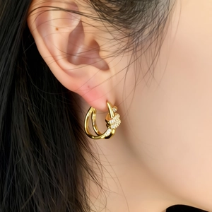 Close-up of gold-plated knotted hoop earring with pavé zircon on woman ear