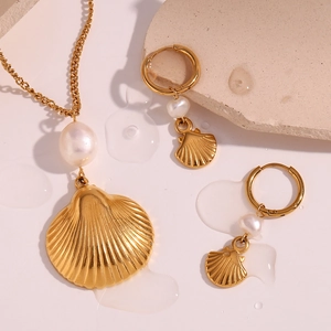 Detailed view of 18K gold plated shell necklace and pearl earrings on a modern pink background