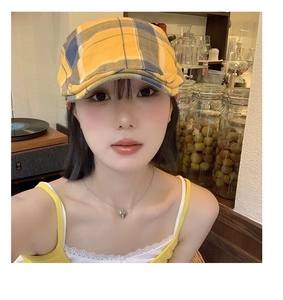 Gros plan sur la casquette gavroche à carreaux jaune et bleu au style vintage Y2K