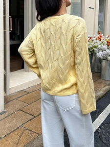 Rear view of woman wearing yellow cable knit sweater in front of a flower shop decor