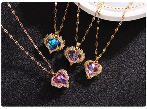 Detail of heart crystal necklaces in blue and purple with gold plating on black background