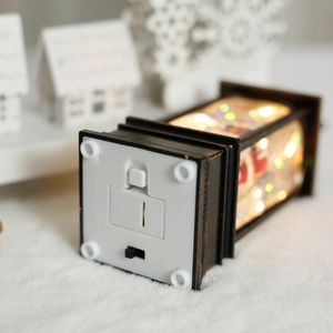 Vintage Christmas lantern with warm LED light and snowflake glitters on white plush base
