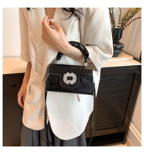 Crocodile texture black shoulder bag with crystal buckle shown on a model