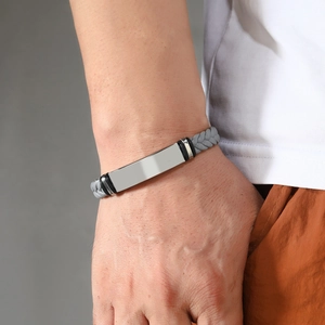Detail of men's braided grey leather bracelet with polished silver rectangle metal plate