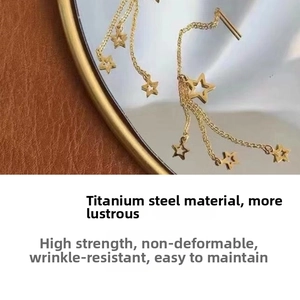 Detail of titanium steel star tassel earrings with long chains in golden finish