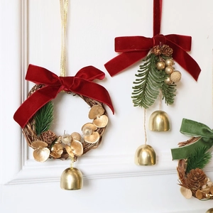 Christmas wreath with red velvet bow, pine cones and gold bells on white background