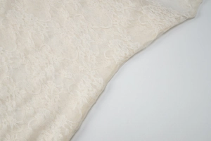 Close-up of delicate off-white floral lace fabric with fine mesh texture and weave