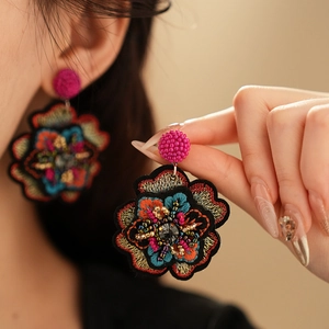 Macro shot of ethnic floral embroidery earrings with colorful beads and dark gemstone