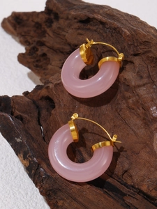 Pink resin hoop earrings with gold metal accents on rustic wood display background
