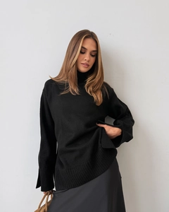Detail of high turtleneck knit sweater featuring stylish slit cuffs in solid black