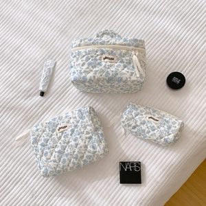Detailed set of three blue floral quilted makeup bags in various sizes with labels