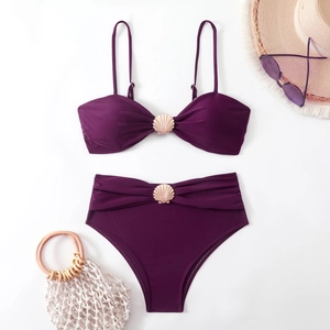 Flat lay of purple bikini with golden shell details and summer beach accessories