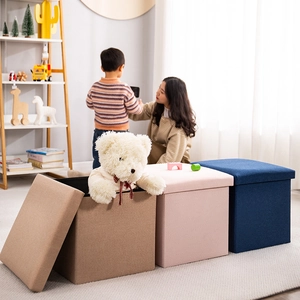 Foldable storage box shown with lid and interior plush toys in a cozy home setting