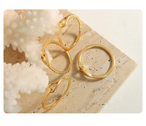 Detailed close-up of a golden twist ring on white coral and warm beige stone props