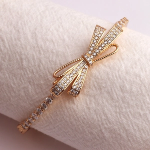 Close-up of luxury gold-plated bow bracelet with sparkling micro-pave zircons on fabric