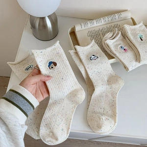 Gros plan de chaussettes beiges avec broderie chiot et neps colorés sur un bureau blanc