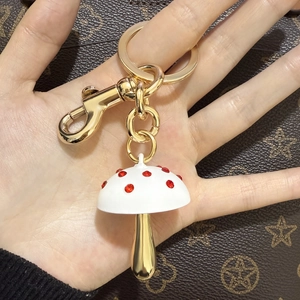 Detailopname van een paddestoel sleutelhanger met rode kristallen aan een handtas