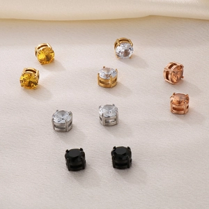 Macro detail of various colors of round zircon magnetic earrings on beige fabric
