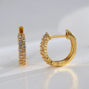 Macro detail of gold plated huggie hoop earrings with micro paved white zircon stones