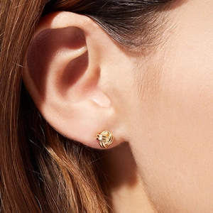 Elegant gold-tone intertwined love knot earrings on a female model's ear lobe