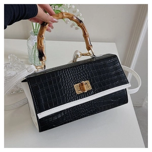 Retro black crocodile texture handbag with white flap and bamboo handle on white desk