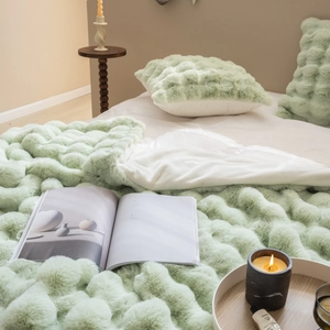 Detail of light green faux fur blanket and pillow with soft 3D bubble texture in cozy bedroom
