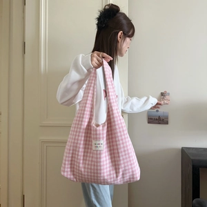 Detailed view of pink and white checkered tote bag held by a model in a natural setting