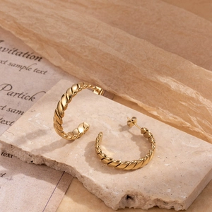 Luxury gold twisted rope C-shaped stainless steel earrings on natural stone background