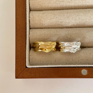 Macro view of gold and silver irregular textured wave rings in a wooden jewelry box