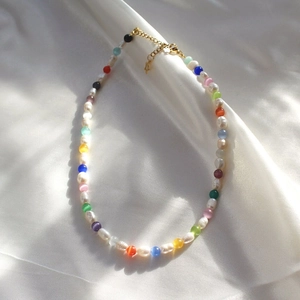 Detail showing irregular pearls and blue cat eye beads on a white satin background