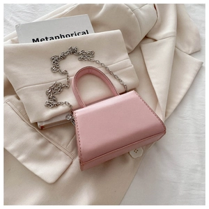 Detailed close-up of a pink bow-knot square bag with silver chain strap on a blazer
