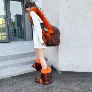 Close-up of fluffy orange faux fur crossbody bag and matching winter boots on model