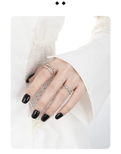 Close-up of dual-layer irregular lines and woven X-shape silver rings on a hand