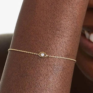 Macro shot of 925 silver golden evil eye bracelet with a sparkling crystal on a model's wrist