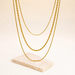 Dettaglio collana a tre strati in acciaio inossidabile 18K oro con maglia a fune e serpente