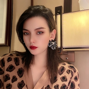 Elegant black bow earrings with sparkling rhinestones worn by a model in a cozy room