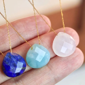 Minimalist gold necklace set featuring teardrop natural stone pendants held by hand
