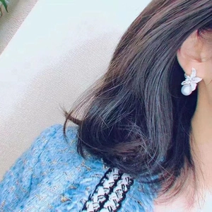 Elegant silver starfish earrings with zircon petals and a white pearl drop on a model