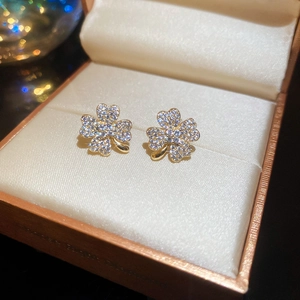 Macro shot of sparkling clover earrings with pavé zircons in a premium jewelry box display