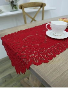 Close-up of a red crochet Christmas table runner with intricate hollow lace patterns